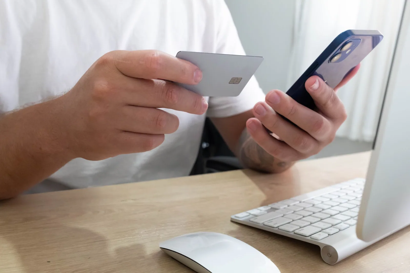 Bank card and smartphone held over a desk