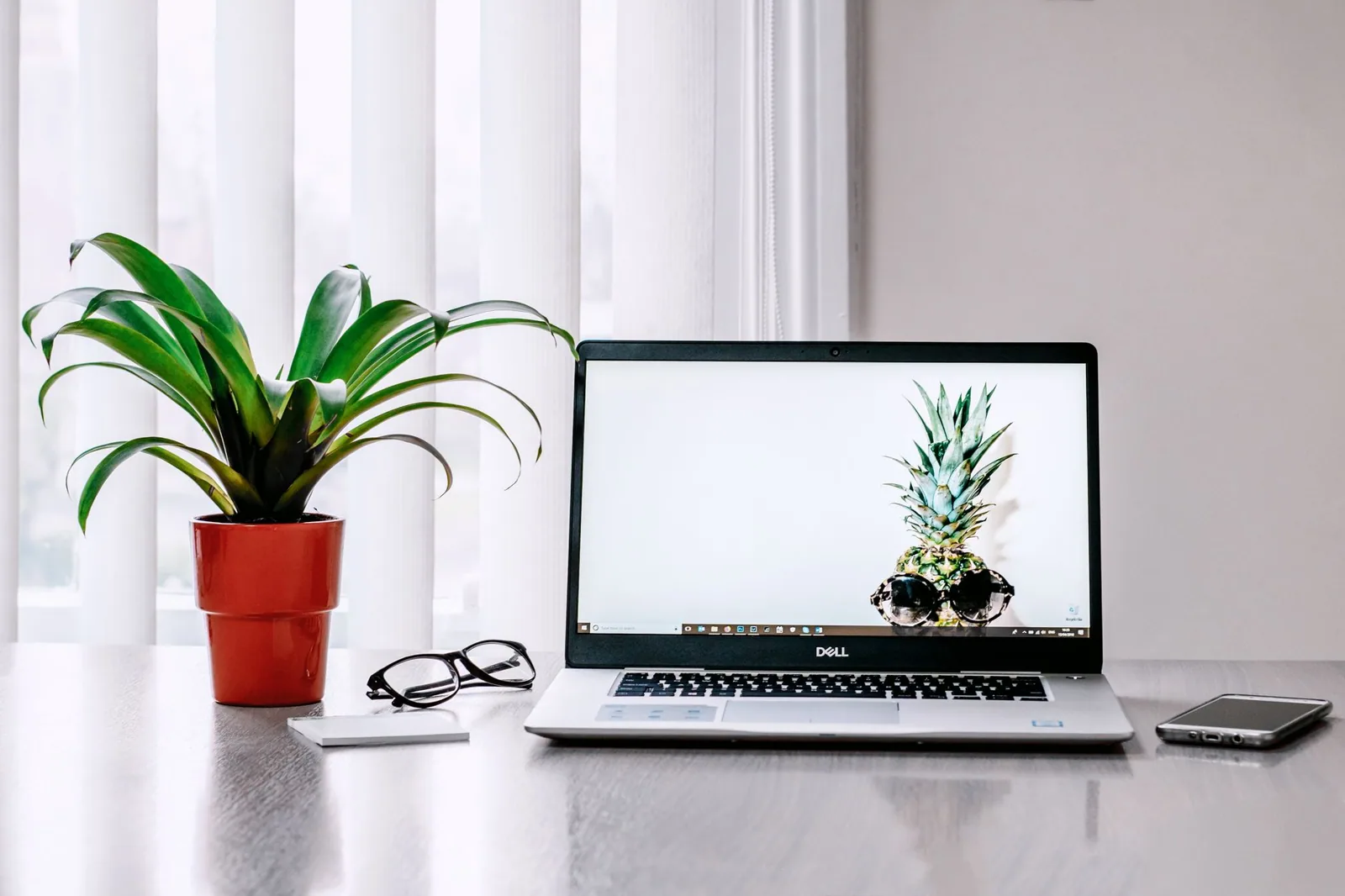 Home office desk with a laptop, plant and phone