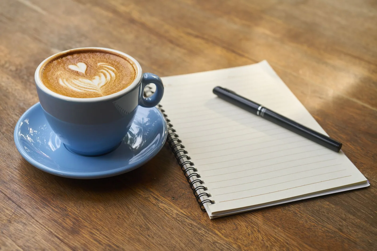 Coffee cup beside an open notebook and pen